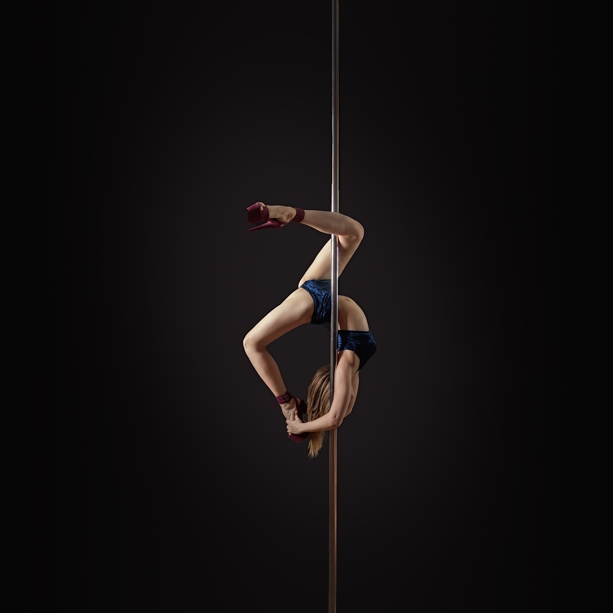 Pole performance — inverted pose against black